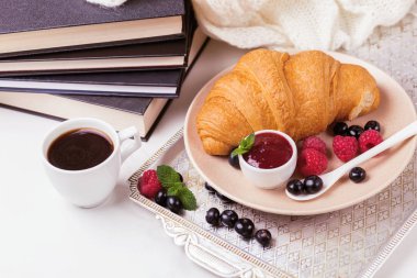 Bir fincan sıcak kahve, kruvasan, ekose ve kitap masada. Eğitim kavramı. Seçici odak