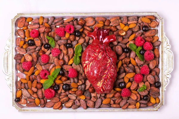 Healthy food and heart model. Nuts and berries. Medical abstract concept