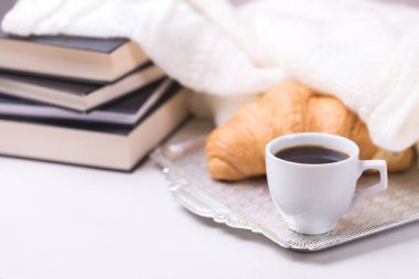 Bir fincan sıcak kahve, kruvasan, ekose ve kitap masada. Eğitim kavramı. Seçici odak