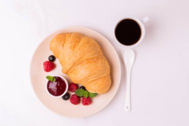 Bir fincan sıcak kahve, reçel ve meyveler kahvaltıda taze kruvasan. Seçici odak