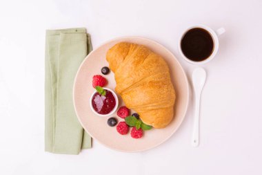 Bir fincan sıcak kahve, reçel ve meyveler kahvaltıda taze kruvasan. Seçici odak