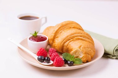 Bir fincan sıcak kahve, reçel ve meyveler kahvaltıda taze kruvasan. Seçici odak