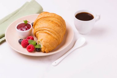 Bir fincan sıcak kahve, reçel ve meyveler kahvaltıda taze kruvasan. Seçici odak