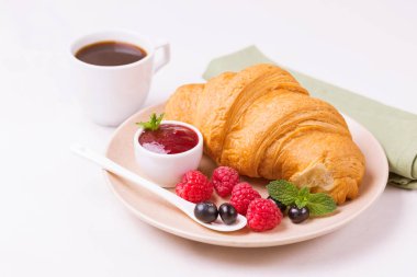 Bir fincan sıcak kahve, reçel ve meyveler kahvaltıda taze kruvasan. Seçici odak