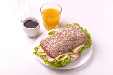 Jambon, peynir ve marul, kahvaltıda kahve ve portakal suyu fincan Chiabatta sandviç. Seçici odak