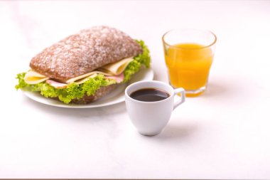 Jambon, peynir ve marul, kahvaltıda kahve ve portakal suyu fincan Chiabatta sandviç. Seçici odak