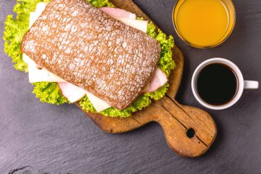 Jambon, peynir ve marul, kahvaltıda kahve ve portakal suyu fincan Chiabatta sandviç. Seçici odak