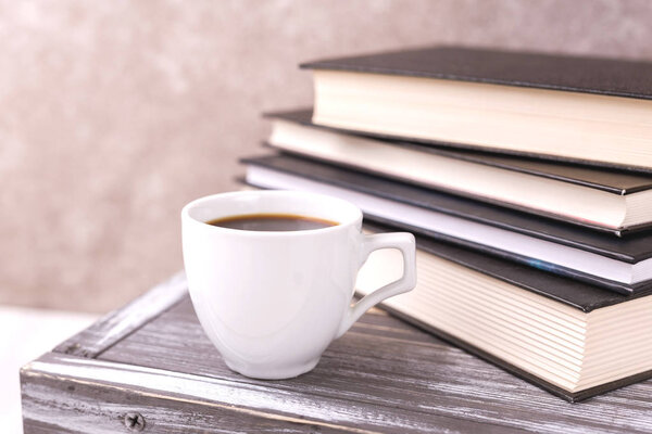 Cup of hot coffee, plaid and books on table. Education concept. Selective focus
