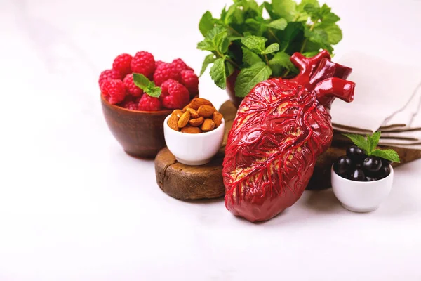 Sağlıklı gıda ve kalp model beyaz tabakta. Fındık ve çilek. Tıbbi soyut kavram