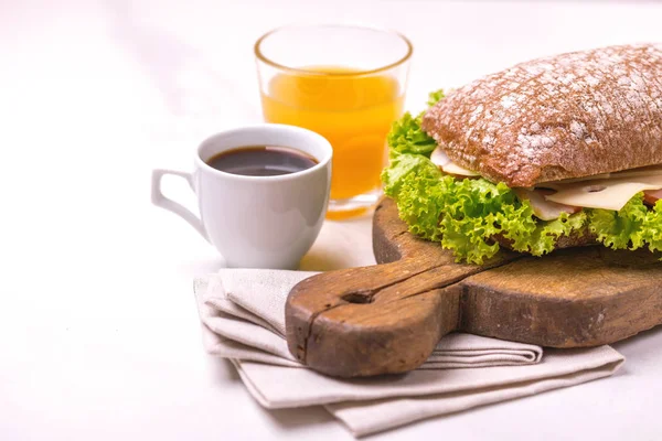 Jambon, peynir ve marul, kahvaltıda kahve ve portakal suyu fincan Chiabatta sandviç. Seçici odak