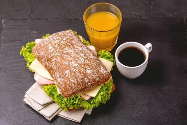 Jambon, peynir ve marul, kahvaltıda kahve ve portakal suyu fincan Chiabatta sandviç. Seçici odak
