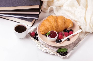 Bir fincan sıcak kahve, kruvasan, ekose ve kitap masada. Eğitim kavramı. Seçici odak