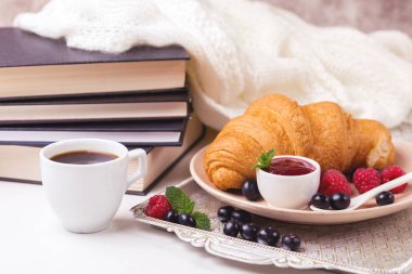 Bir fincan sıcak kahve, kruvasan, ekose ve kitap masada. Eğitim kavramı. Seçici odak