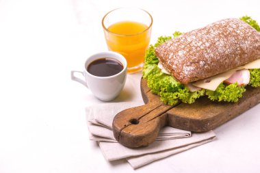 Jambon, peynir ve marul, kahvaltıda kahve ve portakal suyu fincan Chiabatta sandviç. Seçici odak