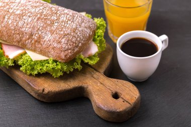 Jambon, peynir ve marul, kahvaltıda kahve ve portakal suyu fincan Chiabatta sandviç. Seçici odak
