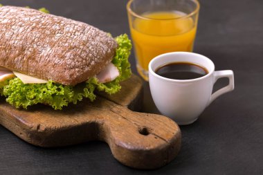 Jambon, peynir ve marul, kahvaltıda kahve ve portakal suyu fincan Chiabatta sandviç. Seçici odak