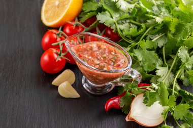 Geleneksel Meksika kırmızı baharatlı sos salsa gri slater arka plan üzerinde malzemelerle. Boşaltmak