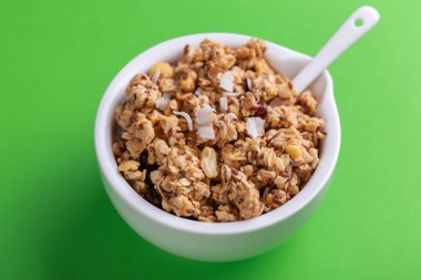 Ev yapımı granola ile fındık ve kuru üzüm yeşil zemin üzerine kase. Üstten görünüm. Kopya alanı