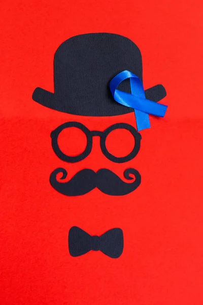 Male silhouette with mustache, glasses and hat patterns and blue ribbon symbol on the red background. Movember concept. Prostate Cancer and men\'s health awareness.