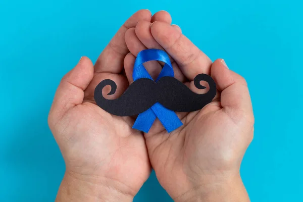 Çocuğun elinde mavi zemin üzerine mavi şerit simgesi olan bıyık desen. Kasım movember kavramı. Prostat kanseri ve erkekler sağlık bilincinin.