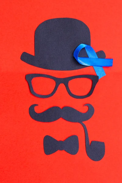 Male silhouette with mustache, glasses and hat patterns and blue ribbon symbol on the red background. November concept. Prostate Cancer and men\'s health awareness.