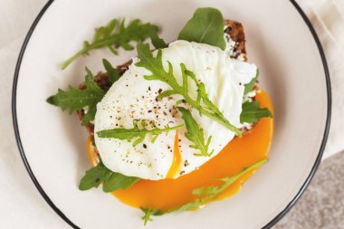 Haşlanmış yumurta, süt krem, baharat ve roka ile çavdar ekmeği tost ve kahve gri arka plan kayrak. Continental kahvaltı. Sağlıklı gıda kavramı. Seçici odak. Yakın çekim. Üstten görünüm