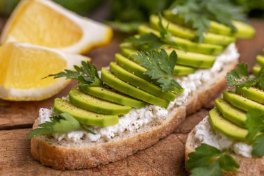 Avokado tost corn bread ile maydanoz, tuz ve biber sağlıklı kahvaltı veya gri kayrak arka plan üzerinde hafif öğle yemeği ile krem peynir. Vejetaryen yiyecekler. Yatay görünüm. Yakın çekim.