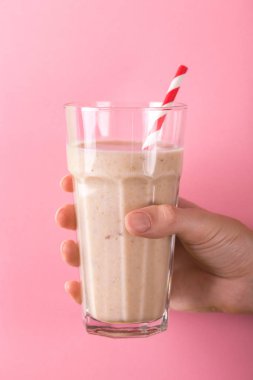 Taze muz ve parlak pembe bir arka plan üzerinde Kağıt pipet ile diş içinde badem güler yüzlü. Yatay görünüm. Kopya alanı