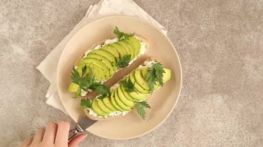 Avokado tost corn bread ile maydanoz, tuz ve biber sağlıklı kahvaltı veya gri kayrak arka plan üzerinde hafif öğle yemeği ile krem peynir. Vejetaryen yiyecekler. Üstten görünüm