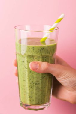 Taze ıspanak ve parlak pembe bir arka plan üzerinde Kağıt pipet ile diş içinde avokado güler yüzlü. Yatay görünüm. Kopya alanı