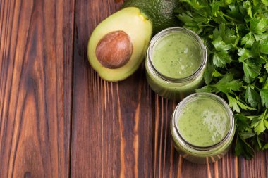 Taze ıspanak ve rustik ahşap zemin üzerine maydanoz ile cam kavanozlara avokado güler yüzlü. Üstten görünüm. Kopya alanı