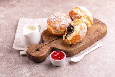 Lezzetli tatlı şekerli çikolata lokmalar frambuaz reçeli ve eski ahşap rustik kesme tahtası üzerinde süt ile. Geleneksel Yahudi tatlı Hanukkah çanak. Gri mermer zemin