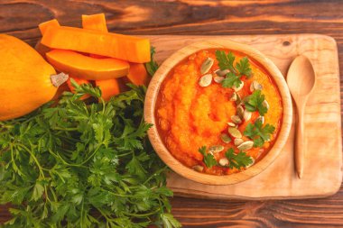 Bright lezzetli balkabağı çorbası kesme tahtası üzerinde malzemelerle ahşap kase ezilmiş. Sağlıklı gıda kavramı. Rustik ahşap arka plan. Üstten görünüm. Kopya alanı