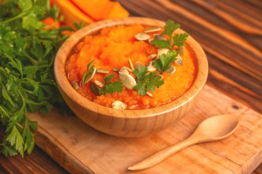 Bright lezzetli balkabağı çorbası kesme tahtası üzerinde malzemelerle ahşap kase ezilmiş. Sağlıklı gıda kavramı. Rustik ahşap arka plan. Yatay görünüm. Kopya alanı