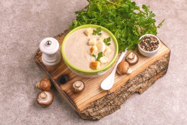 Malzemelerin kesme tahtası üzerine kil kase lezzetli pureed mantar çorbası. Sağlıklı gıda kavramı. Gri ahşap arka plan. Yatay görünüm. Kopya alanı