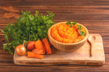 Bright lezzetli pureed havuç çorbası kesme tahtası üzerinde malzemelerle ahşap kase. Sağlıklı gıda kavramı. Rustik ahşap arka plan. Yatay görünüm. Kopya alanı