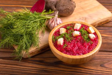 Bright lezzetli kırmızı pancar çorbası kesme tahtası üzerinde malzemelerle ahşap kase ezilmiş. Sağlıklı gıda kavramı. Rustik ahşap arka plan. Yatay görünüm. Kopya alanı