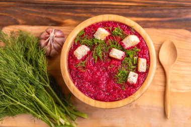 Bright lezzetli kırmızı pancar çorbası kesme tahtası üzerinde malzemelerle ahşap kase ezilmiş. Sağlıklı gıda kavramı. Rustik ahşap arka plan. Üstten görünüm. Kopya alanı