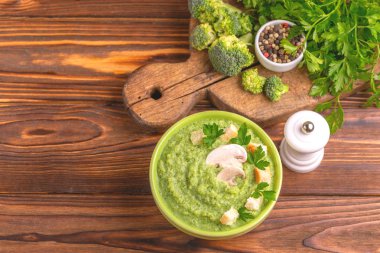 Lezzetli taze brokoli çorbası malzemeler kesme tahtası üzerinde kil kase ezilmiş. Sağlıklı gıda kavramı. Rustik ahşap arka plan. Üstten görünüm. Kopya alanı