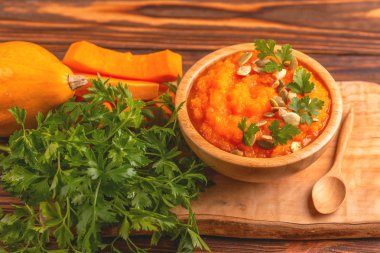 Bright lezzetli balkabağı çorbası kesme tahtası üzerinde malzemelerle ahşap kase ezilmiş. Sağlıklı gıda kavramı. Rustik ahşap arka plan. Yatay görünüm. Kopya alanı