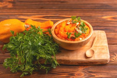 Bright lezzetli balkabağı çorbası kesme tahtası üzerinde malzemelerle ahşap kase ezilmiş. Sağlıklı gıda kavramı. Rustik ahşap arka plan. Yatay görünüm. Kopya alanı