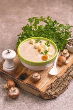Malzemelerin kesme tahtası üzerine kil kase lezzetli pureed mantar çorbası. Sağlıklı gıda kavramı. Gri ahşap arka plan. Yatay görünüm. Kopya alanı