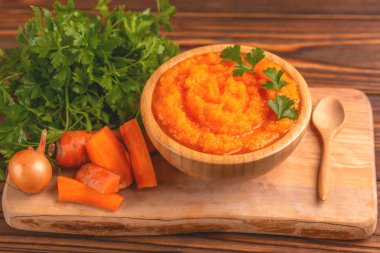 Bright lezzetli pureed havuç çorbası kesme tahtası üzerinde malzemelerle ahşap kase. Sağlıklı gıda kavramı. Rustik ahşap arka plan. Yatay görünüm. Kopya alanı