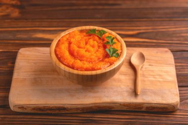 Bright lezzetli pureed havuç çorbası kesme tahtası üzerinde ahşap kase. Sağlıklı gıda kavramı. Rustik ahşap arka plan. Yatay görünüm. Kopya alanı