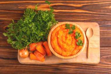 Bright lezzetli pureed havuç çorbası kesme tahtası üzerinde malzemelerle ahşap kase. Sağlıklı gıda kavramı. Rustik ahşap arka plan. Üstten görünüm. Kopya alanı