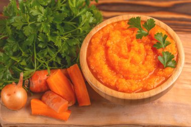 Bright lezzetli pureed havuç çorbası kesme tahtası üzerinde malzemelerle ahşap kase. Sağlıklı gıda kavramı. Rustik ahşap arka plan. Yatay görünüm. Kopya alanı