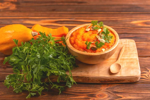 Bright lezzetli balkabağı çorbası kesme tahtası üzerinde malzemelerle ahşap kase ezilmiş. Sağlıklı gıda kavramı. Rustik ahşap arka plan. Yatay görünüm. Kopya alanı