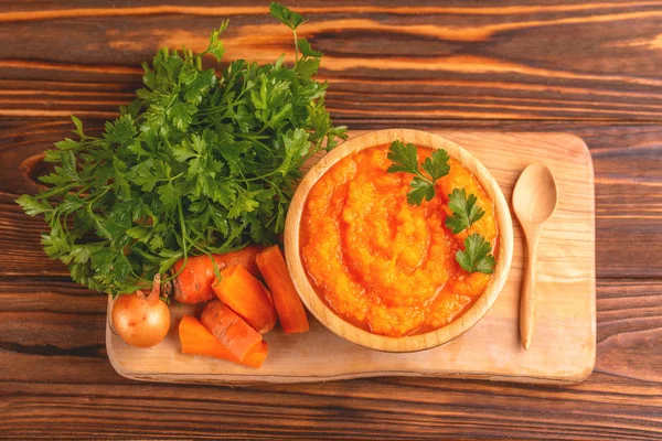 Bright lezzetli pureed havuç çorbası kesme tahtası üzerinde malzemelerle ahşap kase. Sağlıklı gıda kavramı. Rustik ahşap arka plan. Üstten görünüm. Kopya alanı