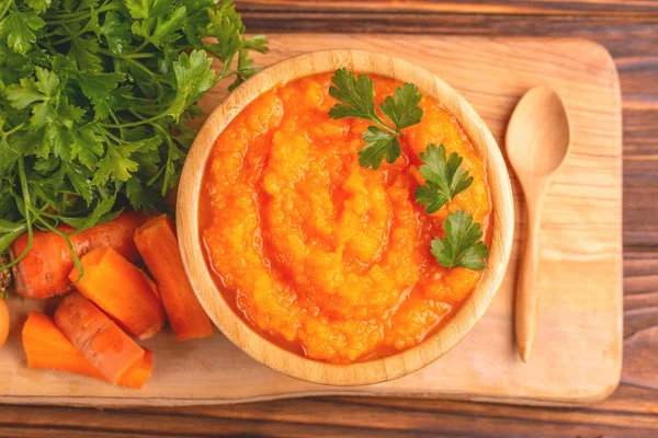 Bright lezzetli pureed havuç çorbası kesme tahtası üzerinde malzemelerle ahşap kase. Sağlıklı gıda kavramı. Rustik ahşap arka plan. Üstten görünüm. Kopya alanı