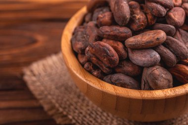 Aromatik ham kakao çekirdekleri çuval bezi peçete ile dolu ahşap arka plan üzerinde top. Yatay görünüm. Kopya alanı